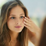 Woman looking in mirror touching skin